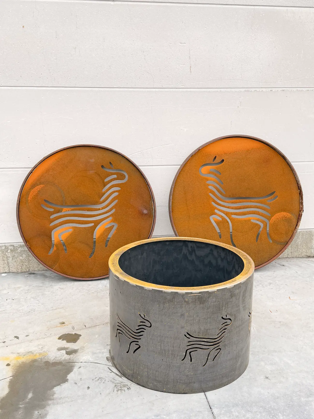 Ronde bloembak in cortenstaal met uitgesneden alpaca‑figuren.