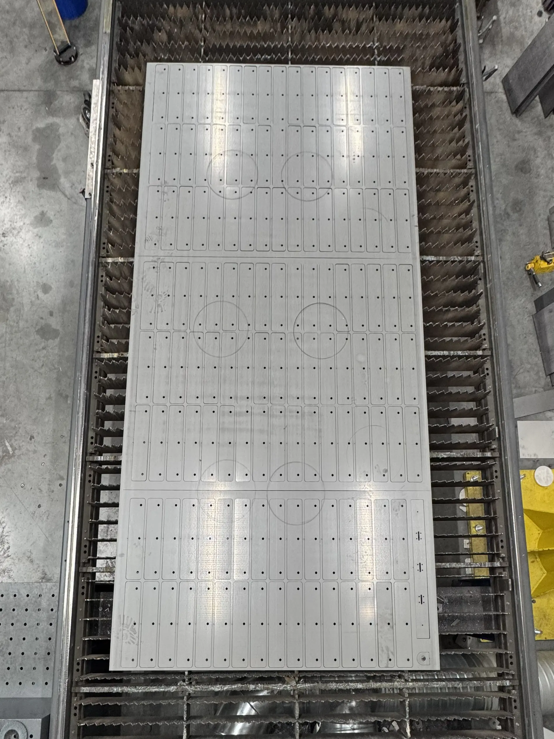 lasersnijden-beugels-staal-5mm Precisie lasergesneden stalen beugels zichtbaar op het laserbed na het snijproces.